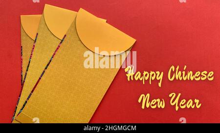 Frohe chinesische Neujahrswünsche auf einem roten Umschlag mit goldenem Kuverthintergrund. Chinesisches Neujahrskonzept. Stockfoto