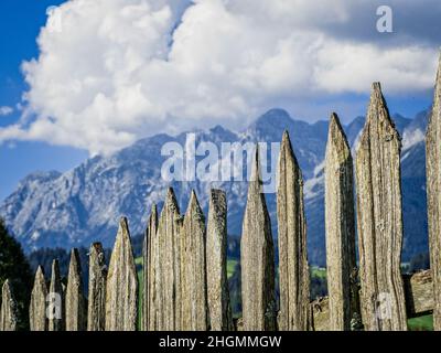 Ein alter Zaun aus Holzlatten vor einem imposanten Bergpanorama. Stockfoto