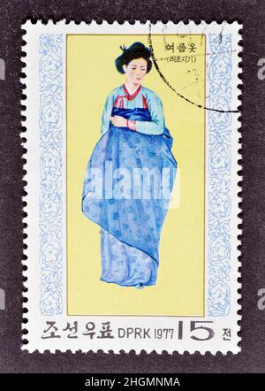 Abgesagte Briefmarke gedruckt von Nordkorea, die Nationalkostüm zeigt, um 1977. Stockfoto