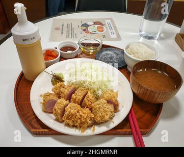 Tonkatsu, ein japanisches Schweineschnitzel mit Kohlsalat, Wasabi und Trüffelöl. Serviert mit Reis und Misosuppe. Stockfoto