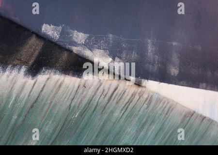 Farbenfrohe Farbarbeiten und Salzlinien am Rumpf eines Fischerbootes auf Holy Island an der Küste von Northumberland - abstrakte Detailaufnahme Stockfoto