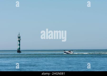Sandbank mit Schnellboot und Leuchtturm in der Nähe der Halbinsel Troia bei Setubal. Lissabon, Portugal Stockfoto