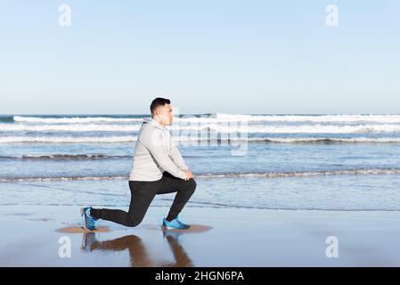 Lateinischer Mann, der am Meer Psoas dehnt Stockfoto