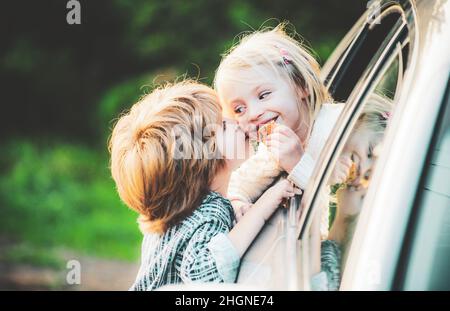 Glücklich lächelndes kleines Mädchen sagt Auf Wiedersehen zu kleinen Freund, der lange Zeit segelt. Gibt einen warmen Kuss. Ein Paar sagte vor der Autofahrt Auf Wiedersehen Stockfoto