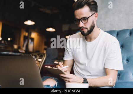 Qualifizierter Mann sucht informative Publikation während der Ausbildung Studium über Netbook Stockfoto