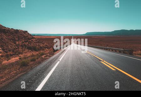 Ländliche Asphaltstraße zwischen den Feldern in der Sommersaison. Stockfoto