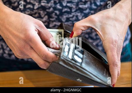 Nahaufnahme der Hand einer Frau, die Geld in eine Brieftasche legt Stockfoto