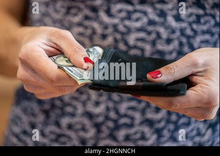 Nahaufnahme der Hand einer Frau, die Geld in eine Brieftasche legt Stockfoto