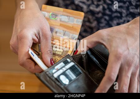 Nahaufnahme der Hand einer Frau, die Geld in eine Brieftasche legt Stockfoto