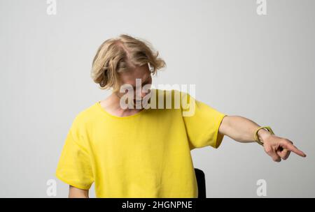 Junger brutaler wütender Mann in gelbem T-Shirt schreit auf jemand über weißem Hintergrund. Gesichtsausdruck. Verrückter Mann. Negative Emotionen, Probleme. Gestresst Stockfoto