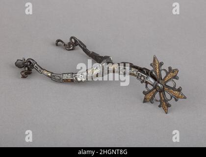 Rowel Spur (rechts) Anfang des 17th. Jahrhunderts britisch oder deutsch die besonders reiche Dekoration dieses Sporns zeigt zarte, goldverstaute Schriftrollen und rechteckige Medaillons, die mit Silberrosen eingelegt sind. Die Innenseiten der Zweige sind sogar mit silbern gedämpften vegetalen Schriftrollen geschmückt, die vor geschwärztem Hintergrund herausstehen. Diese Art der Dekoration findet sich oft auf deutschen und britischen Greifhüttern, die Anfang des 17th. Jahrhunderts hergestellt wurden.in der ersten Hälfte des 17th. Jahrhunderts lag der Modetrend für Herren darin, Stiefel und Spornen auch unter nicht-Reitbedingungen zu tragen, auch zum Tanzen oder Gehen Stockfoto