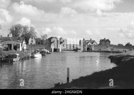 1962, historisch, Blick aus dieser Zeit über die Themse zur Brücke, Abingdon, Oxford, England, Großbritannien. Links festgemacht an einem Bootshaus oder einer Garage mit Benzinpumpen für cleveland-Kraftstoff. Stockfoto