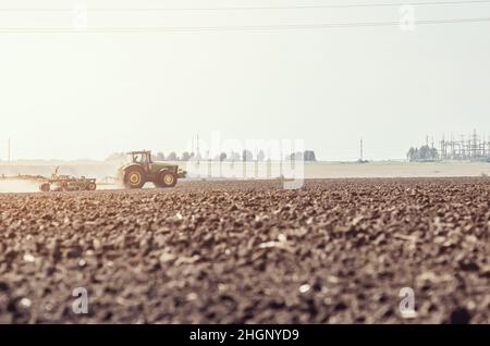 Nebliger Morgen auf dem Feld im frühen Frühjahr. Traktor pflügt chernozem. Stockfoto