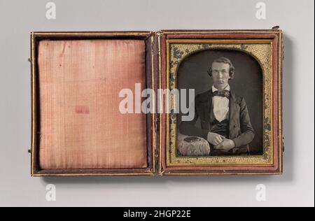 [Sitzender junger Mann, der neben dem Fall Daguerreotypie am Tisch liegt] 1840s Unbekannt der Daguerreotypus, das erste fotografische Verfahren, wurde von Louis-Jacques-Mandé Daguerre (französisch, 1787–1851) erfunden und verbreitete sich nach seiner Präsentation in Paris 1839 rasch auf der ganzen Welt. Jede hochglanzpolierte versilberte Kupferplatte, die in einer Camera Obscura ausgesetzt und in Quecksilberdämpfen entwickelt wurde, ist ein einzigartiges Foto, das bei richtiger Beleuchtung außergewöhnliche Details und Dreidimensionalität aufweist. Der Daguerreotyp wurde in den Vereinigten Staaten, wo er in den Jahren 1840s und 18 sehr populär wurde Stockfoto