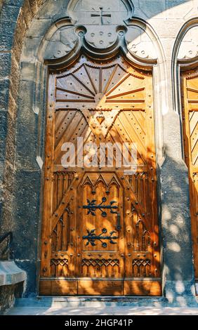 Alte hölzerne Kirchentür mit schmiedeeisernem Muster, verziert mit Metallelementen Stockfoto