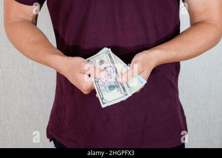 Ein Mann hält einen Geldwad in den Händen. US-Dollar Stockfoto