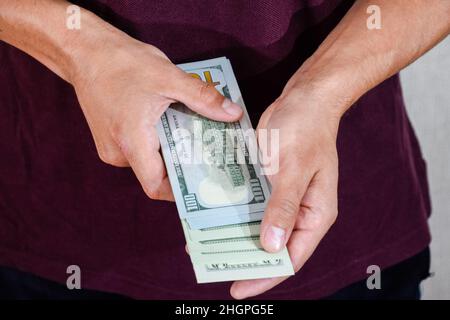 Ein Mann hält einen Geldwad in den Händen. US-Dollar Stockfoto