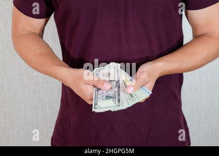 Ein Mann hält einen Geldwad in den Händen. US-Dollar Stockfoto