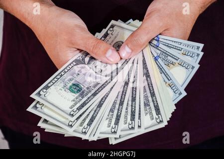 Ein Mann hält einen Geldwad in den Händen. US-Dollar Stockfoto