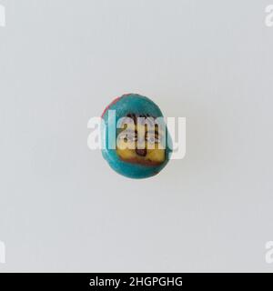 Inlay / Perlenrohling mit Gesicht 100 v. Chr.–100 n. Chr. Ptolemäische Periode–Römische Zeit Eine Mosaikglas-Technik ermöglichte die Schaffung von Vielfachen eines Bildes: Eine figürliche oder gestalterische Komposition wurde durch Bündelung von farbigen Glasstöcken hergestellt, die dann zu einem langen Stab herausgezogen wurden. Die Stange wurde dann im rechten Winkel geschnitten, wahrscheinlich durch Aufschlagen der Stange mit geeigneten Werkzeugen, um kleine Inlay-Fliesen zu produzieren. Die Fliese würde dann geglättet und auf dem Gesicht poliert, das nach außen erscheinen soll. Inlay / Perle blank mit Gesicht. 100 V. CHR.–100 N. CHR. Glas. Ptolemäische Periode–Römische Periode. Aus Ägypten Stockfoto