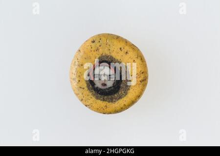 Inlay / Perlenrohling mit Gesicht 100 v. Chr.–100 n. Chr. Ptolemäische Periode–Römische Zeit Eine Mosaikglas-Technik ermöglichte die Schaffung von Vielfachen eines Bildes: Eine figürliche oder gestalterische Komposition wurde durch Bündelung von farbigen Glasstöcken hergestellt, die dann zu einem langen Stab herausgezogen wurden. Die Stange wurde dann im rechten Winkel geschnitten, wahrscheinlich durch Aufschlagen der Stange mit geeigneten Werkzeugen, um kleine Inlay-Fliesen zu produzieren. Die Fliese würde dann geglättet und auf dem Gesicht poliert, das nach außen erscheinen soll. Inlay / Perle blank mit Gesicht. 100 V. CHR.–100 N. CHR. Glas. Ptolemäische Periode–Römische Periode. Aus Ägypten Stockfoto