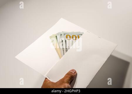 Dollar im Wind auf weißem Hintergrund, viel Geld in einem Umschlag. Stockfoto