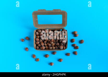 Box mit Haselnüssen über Stein Tisch, einem blauen Hintergrund Flatlay Stockfoto