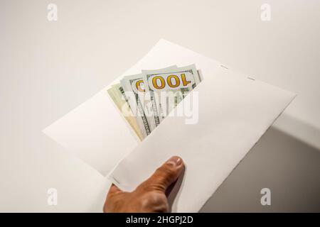 Dollar im Wind auf weißem Hintergrund, viel Geld in einem Umschlag. Stockfoto