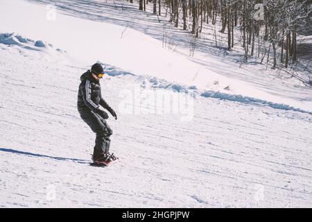 Mann in warmen Kleidern Snowboarding Downhillfreestyle. Wintersportkonzept. Extremsport in der Wintersaison. Snowboarder genießen Extremsport. Stockfoto