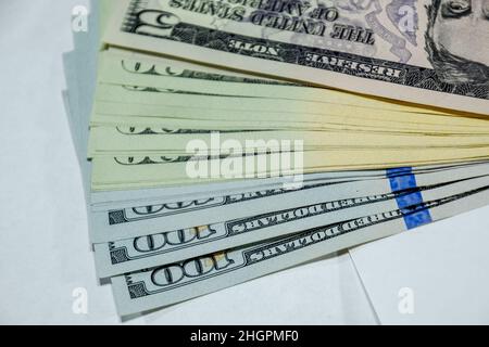 Die Zisterne der Banknoten liegt auf einem weißen Tisch. Viele Dollar, ein Haufen Dollar. Stockfoto