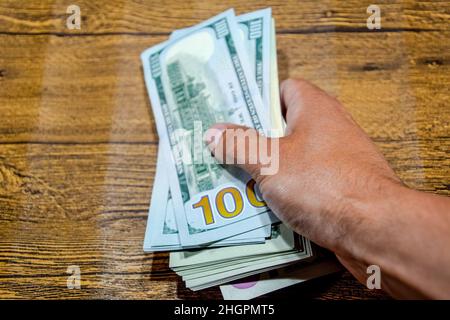 Der Mann am Tisch hält Rechnungen. Dollar in der Hand. Stockfoto