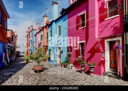 Schmale Straße mit bunten Häusern mit Waschanlagen auf der Insel Burano, Venedig, Italien gesäumt Stockfoto