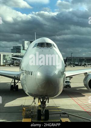 Schriftart eines modernen Flugzeugs, das in einem Flughafen geparkt ist. Nahaufnahme aus Weitwinkelaufnahmen mit schweren Wolken. Stockfoto