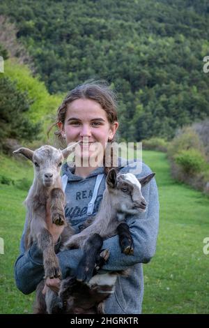 Janira posiert mit einem Ziegenling. Tägliches Leben, in einem traditionellen Bauernhof in den Bergen, Roni Dorf, Alt Pirineu Naturpark, Lleida, Katalonien, Spanien Stockfoto