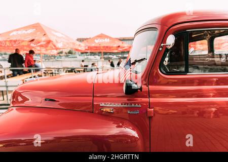 Seitenansicht des Red International Harvester R-Serie Trucks mit kleiner amerikanischer Flagge, der in der Straße geparkt ist. Stockfoto