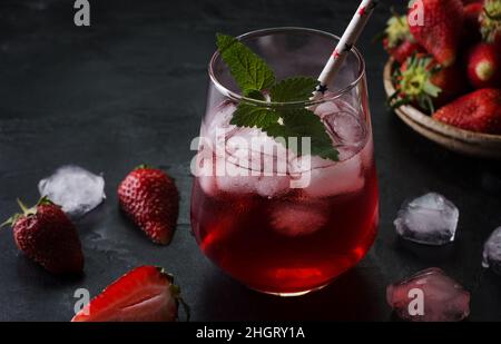 Kalter Cocktail mit Erdbeeren und Eis auf schwarzem Hintergrund. Sommerliche Drinks auf dunkle Art und Weise. Stockfoto