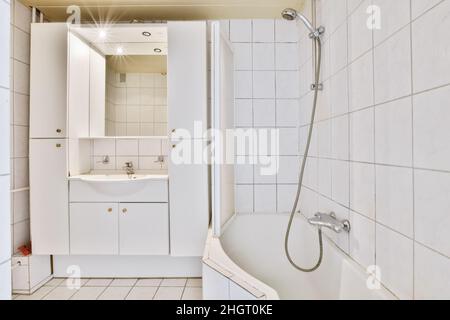 Modernes Badezimmer mit weißen Fliesenwänden und -Boden sowie einer Badewanne Stockfoto