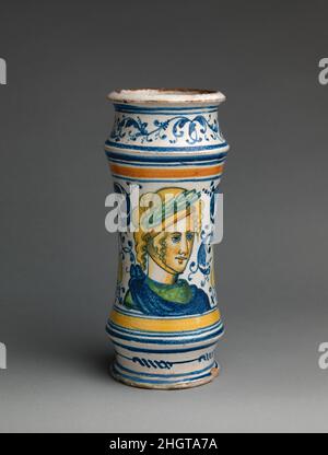 Apothekendose (albarello) wahrscheinlich ca. 1542 Werkstatt von Masséot Abaquesne mit Lorbeerkranz und klassischem Draperie ist die weibliche Figur, die auf diesem Glas inmitten des rollenden Laubes dargestellt ist, detaillierter als der Profilkopf auf dem in der Nähe gezeigten Beispiel, Der Eindruck, dass diese nicht Teil der sehr großen und skizzenhaft ausgeführten Bestellung für pharmazeutische Behälter gewesen sein könnte, die 1545 bei Masséot Abaquesne platziert wurde. Apothekenbecher (albarello). Französisch, Rouen. Wahrscheinlich ca. 1542. Zinnglasierte Steingut. Keramik-Keramik Stockfoto