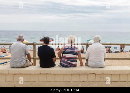 Blanes, Katalonien, Spanien. - am 25. Juli 2017 sitzt Eine Gruppe älterer Menschen auf der Brüstung und blickt auf das Meer. Blick von hinten Stockfoto