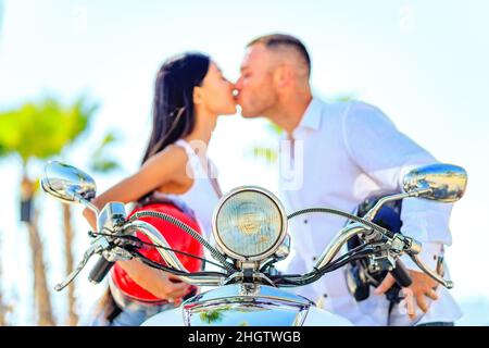 Schönes junges Paar in einem Helm auf einem Roller im tropischen Paradies Strand reiten Stockfoto