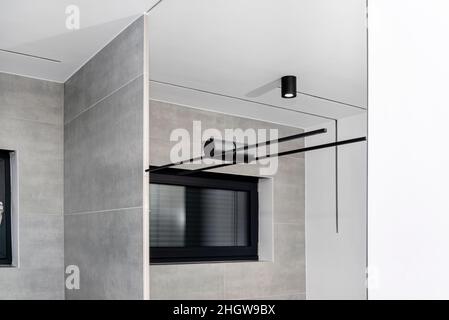 Schwarzes Kinket in einem großen Spiegel im Badezimmer montiert, sichtbare LED-Beleuchtung in Form einer Röhre. Stockfoto