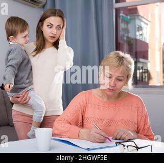 Erwachsene Frauen mit ihrer Mutter haben Unstimmigkeiten wegen Problemen beim Ausfüllen von Dokumenten Stockfoto