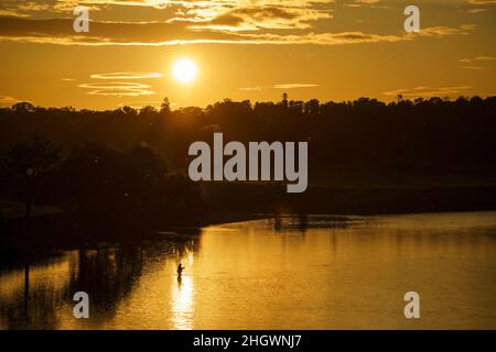 Ein Angler steht im rhe Junction Pool, wo die Flüsse Teviot und Tweed zusammenfließen, in Kelso, Schottland, wo die Sonne Anfang Juni untergeht Stockfoto