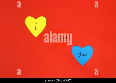 Valentinstag Herzen auf vintage roten Hintergrund als Valentinstag Symbol. Herzförmige Notizpapiere mit „I Love You“ darauf. Stockfoto