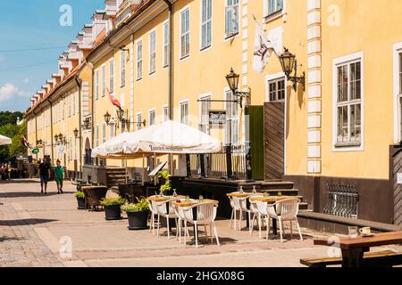 Riga, Lettland. Street Cafe Restaurant in der Altstadt unter den Fassaden der berühmten Jacob's Barracks in der Torna Street. Sonniger Sommertag Mit Blauem Himmel Stockfoto