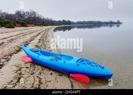 Blaues Kajak auf offenem Wasser im Nebel und Nebel am Loch Lomond Stockfoto