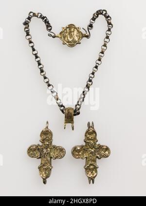 Reliquienanhänger Kreuz 12th–14th Jahrhunderte byzantinischer oder frührussischer (?) Vergoldete silberne Reliquienkreuze waren in der orthodoxen Welt im byzantinischen und postbyzantinischen Jahrhundert beliebt. Dieses Werk überlebt in seiner Gesamtheit. Die beiden Hälften des Reliquiars zeigen Christus und eine thronende Jungfrau, flankiert von Medaillons mit Büsten heiliger Figuren. Die Kette, aus der der Reliquienschrein hing, wird durch einen Verschluss mit einem Bild einer bärtigen Figur geschlossen, die möglicherweise Gott den Vater darstellt. Reliquie Des Hängenden Kreuzes. Byzantinisch oder frührussisch (?). 12th–14th Jahrhunderte. Silber und vergoldetes Silber. Metallarbeiten-Silve Stockfoto