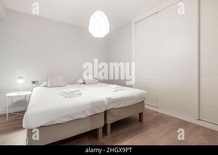 Zimmer mit Doppelbett und Einbauschrank mit Schiebetüren und Holzböden Stockfoto