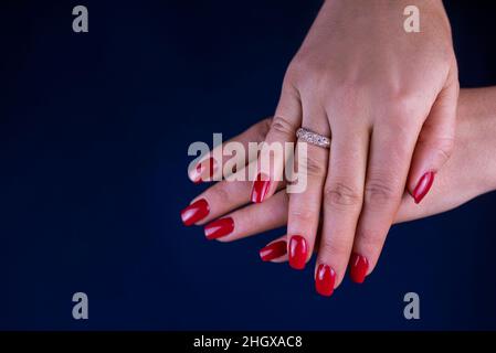 Mädchenhände mit einer roten Maniküre und einem Ring am Finger Stockfoto