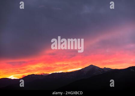 Feuriger Sonnenuntergang hinter den Bergen Stockfoto